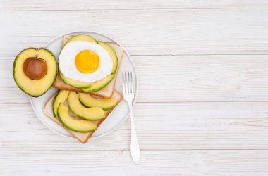 Beyaz ahşap zemin üzerinde avokado ile sağlıklı kahvaltı tostları fotokopi alanı ile maket yatar