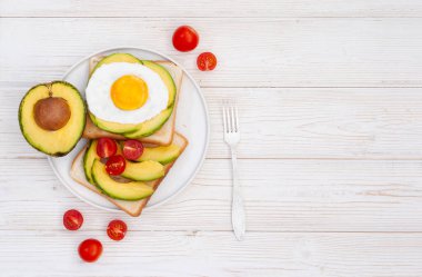 Beyaz ahşap arka planda avokado ile sağlıklı kahvaltı tostları fotokopi alanı ile birlikte düzleştirilir. Vejetaryen sebze yemeği.