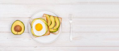 Beyaz ahşap arka planda avokado ile sağlıklı kahvaltı tostları fotokopi alanı ile birlikte düzleştirilir. Vejetaryen sebze yemeği.