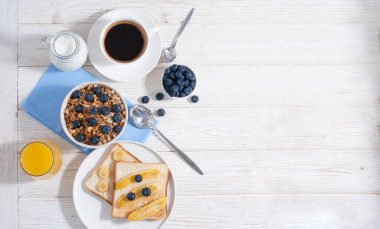 Tahıl gevreği ve yaban mersinli kahvaltı, kahve, portakal suyu ile süt ve beyaz ahşap masa üzerinde pişmiş tost fotokopi alanı ile birlikte yatıyordu. Sabahları yulaf ezmeli sağlıklı yiyecekler.