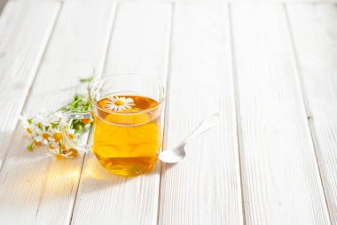 Beyaz ahşap arka planda papatya çiçekli bir fincan bitki çayı. Kopya alanı ile doğal organik alternatif tıp kavramı