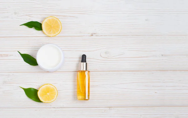 Natural cosmetic oil with lemons beautiful colse-up flat lay composition on the white wooden background with copy space. Skin care concept