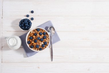 Tahıl gevreği ve yaban mersinli kahvaltı, kahve, portakal suyu ile süt ve beyaz ahşap masa üzerinde pişmiş tost fotokopi alanı ile birlikte yatıyordu. Sabahları yulaf ezmeli sağlıklı yiyecekler.