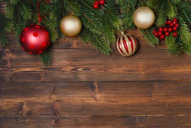 Köknar ağacı dalları ve ahşap arka planda kırmızı ve altın süslemeleri olan yeni yıl ve Noel mokcup 'ı