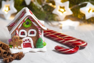 Zencefilli kurabiye evi, şeker kamışı ve doğal baharatlarla Noel süslemesi. İçinde noel ağacı ve çelenk ışıkları olan tarçın ve ananas. Yeni yıl kış tatili tebrik kartı.