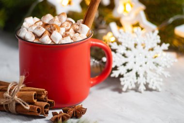 Kırmızı bardakta güzel bir noel içkisi marşmelovlu ve anis yıldızlı tarçınlı. Yeni yıl kış bayramı kutlaması masası. Şenlikli dekorasyonlar