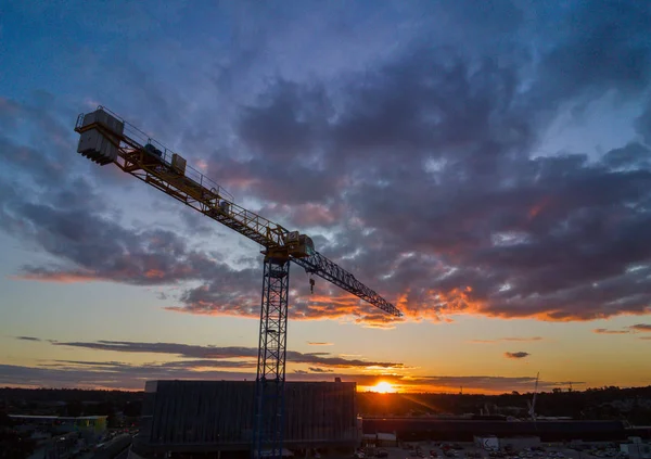 バック グラウンドでの夕日とシルエット クレーン建設タワー — ストック写真