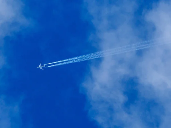 Ένα Αεριωθούμενο Αεροπλάνο Πετά Πέρα Από Ένα Καταγάλανο Ουρανό Νεφώσεις — Φωτογραφία Αρχείου