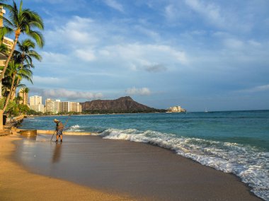 ABD, Hawaii - 29 Ağustos 2018: Waikiki Beach bir metal detektörü kullanan bir adam ile gün batımında