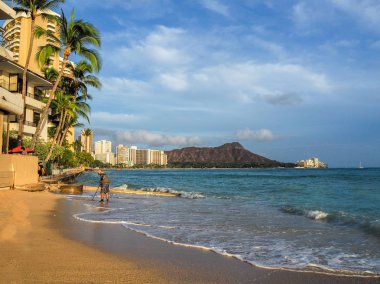 ABD, Hawaii - 29 Ağustos 2018: Waikiki Beach bir metal detektörü kullanan bir adam ile gün batımında
