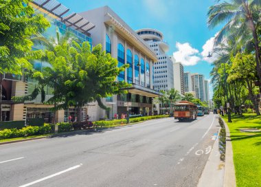 USA, HAWAII - AUGUST 31, 2018: Hawaiin style bus known as a trolley goes down the main strip of Kalakaua Avenue in Waikiki clipart