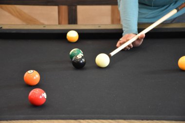 Kara bilardo masası, bilardo oynayan bir adamın yakın plan fotoğrafı.