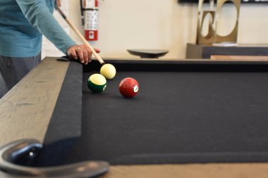 Kara bilardo masası, bilardo oynayan bir adamın yakın plan fotoğrafı.
