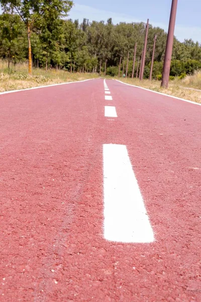 red gummed bike path as a walk in the park, with trees around