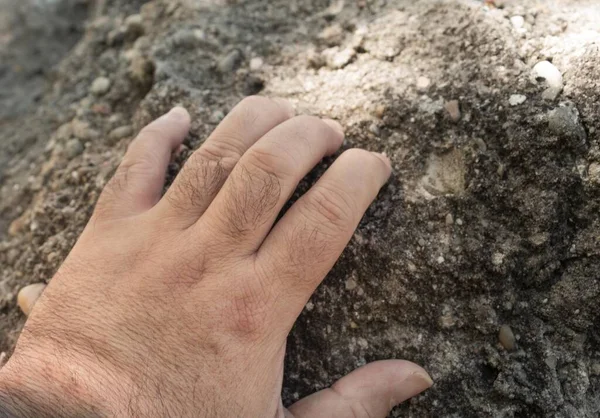 hand grabbing the rock to start a climb on the