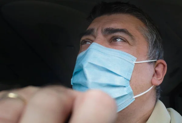 Fifty-year-old man driving a van with a face mask and an unfocused hand