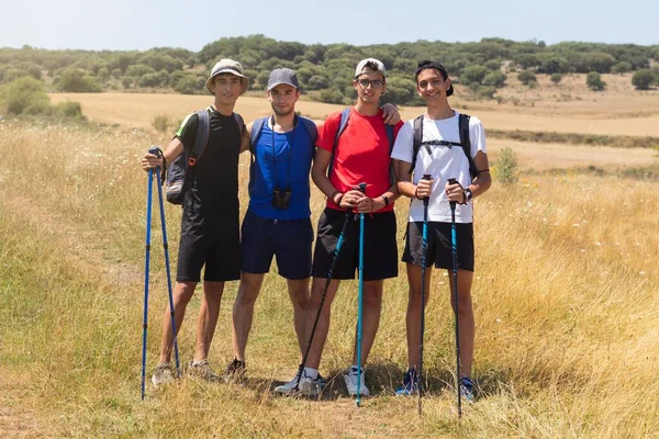 four young people with trekking poles doing the Camino de Santiago in Spain on a summer day