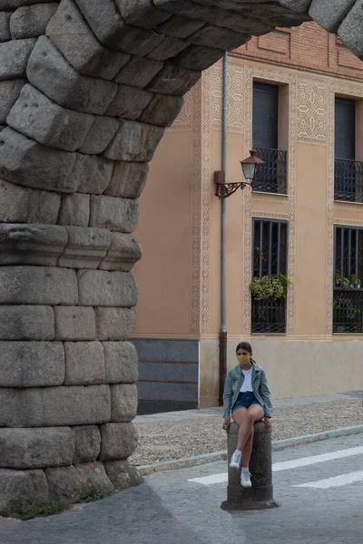 girl sitting on a stone column under an ancient arch in a Roman city on a summer day