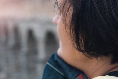 Orta yaşlı bir kadın, arka planda bir Roma köprüsü olan bir yaz gününde ufka bakıyor.