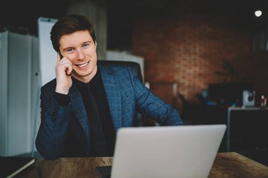Office kamerada bakarak telefon görüşmesi portresi müreffeh iş üstünde hareket eden telefon vasıl okul sırası ile dizüstü bilgisayar, başarılı erkek girişimci oturan söz sahibini memnun