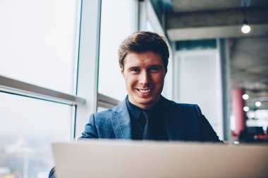 Araştırma online, mutlu icra müdürü yazılım ve kameraya bakarak netbook üzerinde apps güncelleştirme Office çalışma yapmak için dizüstü bilgisayar kullanan neşeli müreffeh işadamı portresi