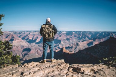 Erkek Gezgin dağ tur, Büyük Kanyon Ulusal Parkı kuru vadide bakarak kayalık tepenin üzerinde sırt çantası duran adamla hipster hiking, hedef için en iyi geçmesini manzarayı arkadan görünüm