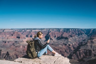 Milli Park, dağ tepe üzerinde yürüyüş sırasında hücresel dinlenme üstünde posta kontrol kadın turist Yolculuk tutkusu kayalık uçurum üzerinden ileti göndermek için mobil bağlantı kullanarak sırt çantası ile gülümseyen kız