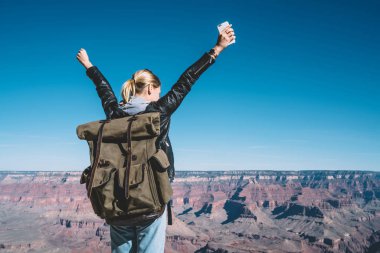 Genç kadın Gezgin Arizona Milli Park, Grand Canyon Vadisi üzerinde kayalık uçurum ayakta eller yükselterek hippi kız duygu özgürlük keşfetmek dağın tepesine ulaşan başarı kutluyor 
