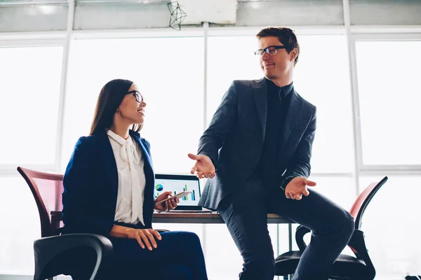 Male and female colleagues in formal outfit having friendly conversation during meeting in office, proud ceo of company discussing plans for working day with secretary assistant explaining details