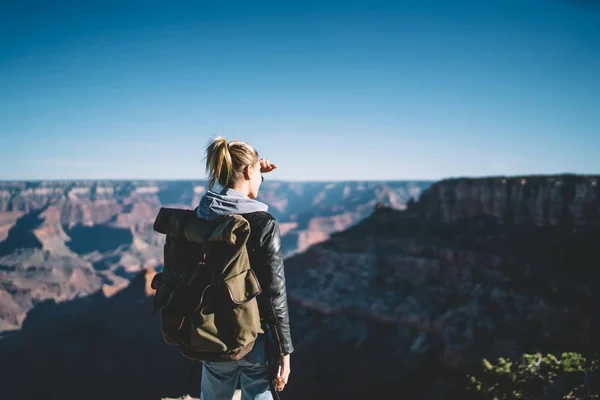 在大峡谷观看美丽自然风景的女性旅行者的背影 时髦的妇女流浪与背包徒步旅行在狂放的自然看在岩石山顶山和谷在阴影 — 图库照片