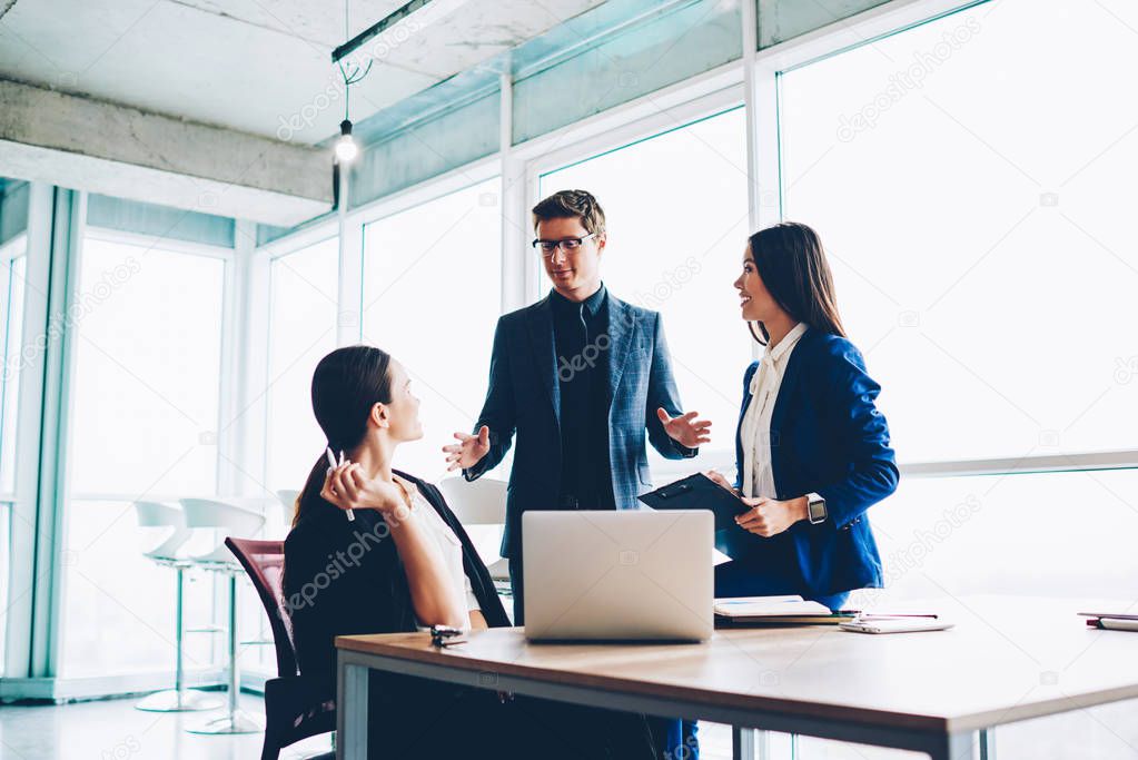 Professional male executive manager explaining to female colleagues strategy for startup presenting idea on meeting,confident boss in formal wear communicating with employees about working tasks