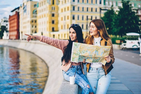 手の右方向にあるマップから観光都市プロモーション背景に立っているランドマークを見つけるために行く場所を表示する都市の魅力的な住民は 若い女性の旅行者に対象を指しています — ストック写真