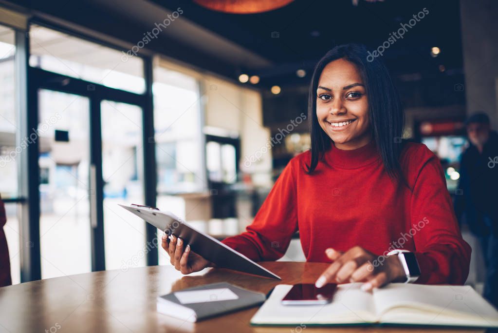 Portrait of afro american businesswoman checking plan for startup satisfied with creative solutions.Prosperous administrative manager making financial research of incomes enjoying job in cafe