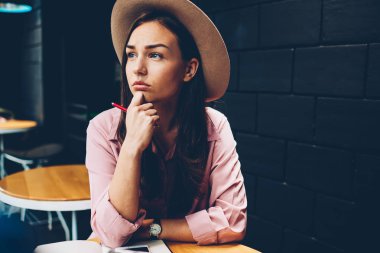 Planları için kafe iç durulması içinde vakit trendy şapkalı güzel hippi kız iş, şık giyimli genç kadın fikir masadan uzakta seyir kalemle yazı için konsantre