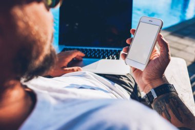 Modern smartphone boş kopya alanı ekran reklam bilgin ile içerik olan dizüstü bilgisayar ile sahte çevre havuzu kadar yaz aylarında yalan elinde tutan adam turist görüntüsünü croped