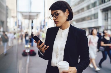 Meşgul sahibi finans şirketi hücresel insanlar kalabalık ile sokakta yürürken üzerinde gelir çıkıyor. E-posta ile kahve geziniyor telefon kontrol zarif aşınmaya ciddi kadın girişimci