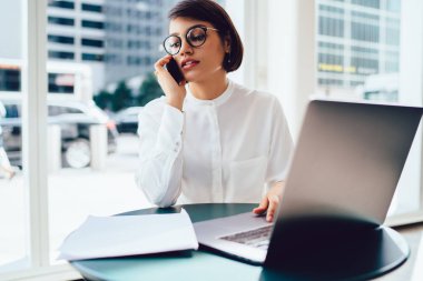 Ciddi işkadını zarif aşınmaya cep telefonunuzda muhasebesi raporu hakkında konuşuyor. Dizüstü bilgisayar ile kafede oturan meslektaşı ile başlatma hakkında telefon görüşme sahip emin girişimci