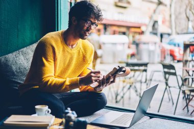 Online webinar izliyor ve notlar alan coworking içinde e-öğrenme sırasında Not Defteri'nde yapım optik gözlük akıllı erkek öğrenci. Metin not defterinde Internet Web sitesinden yazma, zeki genç adam