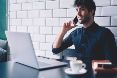 Kablosuz internet şık kafede oturan başarılı girişimci mobil operatör Yöneticisi ile smarthone aygıtta dizüstü bilgisayar başında çalışırken konuşmayı bağlı
