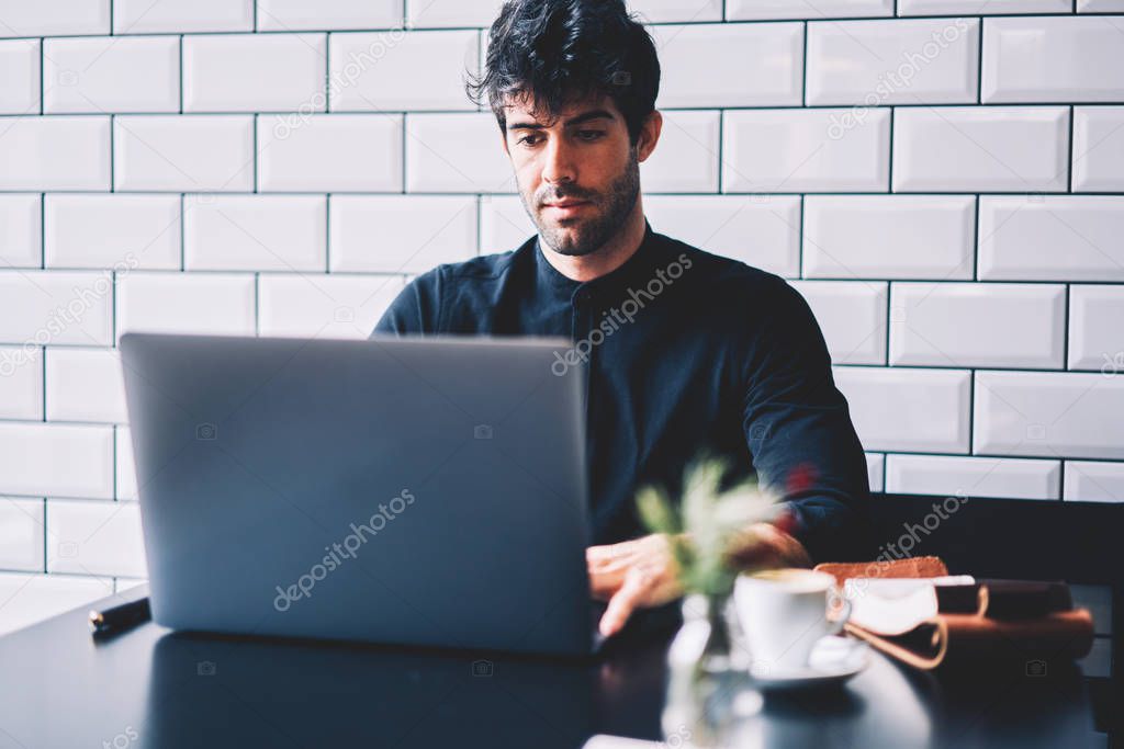 Concentrated it professional working on developing new programme via free high speed internet connection on laptop computer.Male graphic designer creating own website on modern netbook device