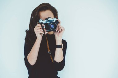 Profesyonel kadın fotoğrafçı fotoğrafları vintage fotoğraf makinesi ayakta reklam metin mesajınız için beyaz promosyon arka plan yapma. Genç kadın boş vaktinizi fotoğraf çekmek