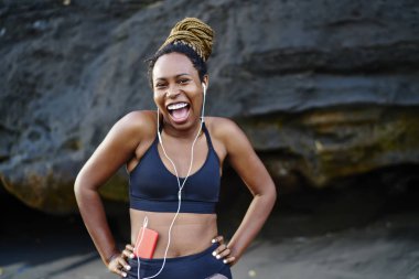 Duygusal olumlu sportif kadın portresi oyuncu smartphone cep telefonu ile komik müzik keyfi etkin elbise giymiş. Neşeli afro Amerikan kadın dinleme şarkıları kulaklık önce spor eğitim