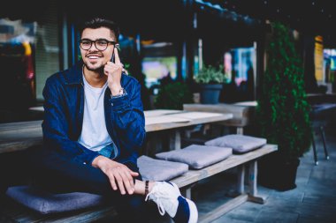 Telefon konuşmalarını, smartphone cep telefonu ile görüşme sırasında kameraya bakarak yakışıklı genç gülümseyen tarifeler ile cep telefonuna arkadaşıyla konuşurken gözlük neşeli hipster adam portresi memnun