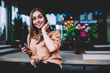 Mutlu genç kadın manifatura iletileri kafe iç giyim serbest zaman sırasında smartphone kullanarak sosyal ağlar sohbet içinde şirin hippi kız gülümseyerek Wi-Fi erişimi ile mobil oturan