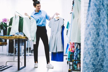 Askıları ile el ve düşünme trendy giyim moda botique çalışma kıyafeti daha iyi varyant üzerinde tutan kadın terzi deneyimli. Yeni görüntü alanı için seçtiğiniz showroom stilist
