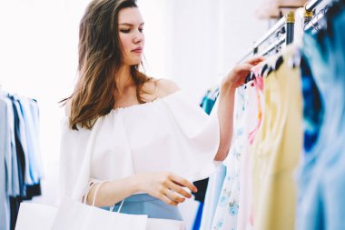 Çekici şık giyimli kadın moda deposunda giysiler seçmek alışveriş için kararı konsantre. Şık güzel erkek giyim showroom trendy bir görünüm oluşturmak için yetenekli tasarımcı aranıyor