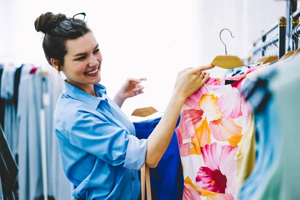 幸せな女性デザイナーを選択するショールームの手でカラフルな服で自身の新しいコレクションの立っているドレスします スタイリスト開発ビジネスのトレンディな織物の生産での作業 — ストック写真