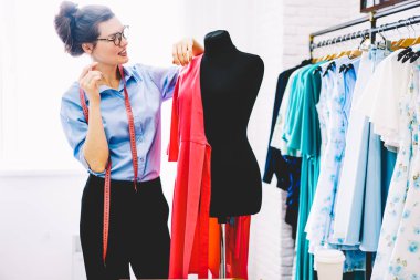 Dikkatli bir şekilde yeni koleksiyonu şık giyim kendi showroom çalışma tasarımını geliştirmek için fikirleri üzerinde düşünürken pembe Tekstil malzeme ile siyah manken seyir yaratıcı kadın modacı