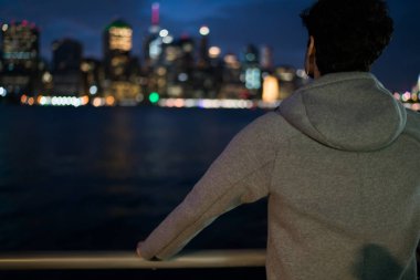 Genç adam Arkadan Görünüm alanı markası ayakta akşam şehir arka plan üzerinde kentsel ortamda için sahte gri spor ceket giymiş. Active giysi sporcu spor giyim etiketli, twilight