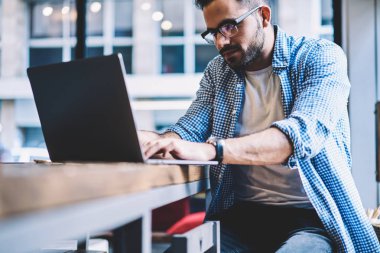 Office, coworking içinde masada oturan dizüstü bilgisayar ağ üzerinde klavye yetenekli erkek freelancer grafik tasarımcı proje için online başvuru kullanarak ağ dizüstü bilgisayarı mesafe işi konsantre